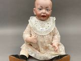 une poupée ancienne en porcelaine représentant un bébé assis par terre