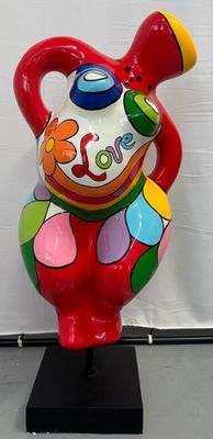 un vase coloré posé sur un socle noir devant un mur blanc