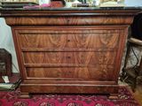 une commode en bois avec un plateau en marbre posée sur un tapis rouge