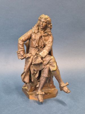 statue en bronze représentant un homme assis sur une chaise, les jambes croisées