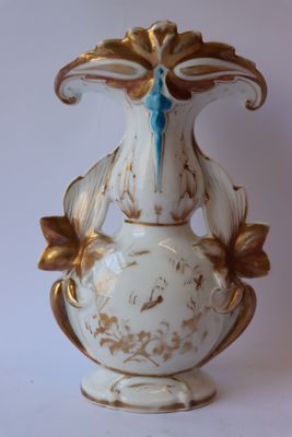 un vase blanc et doré orné d'un nœud bleu