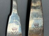 pair of silverware spoons with a crown on each of them