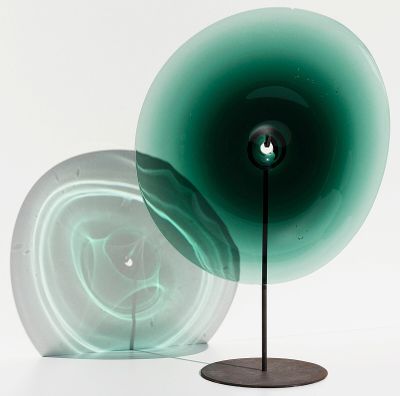 une lampe verte posée sur un pied près d'un mur blanc