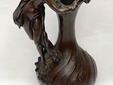 une statue représentant une femme tenant un vase posé sur un socle