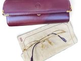 étui à lunettes en cuir violet avec des bords dorés et une paire de lunettes
