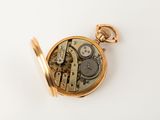 a gold pocket watch on a white surface