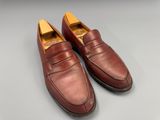 une paire de mocassins marron posée sur une surface grise