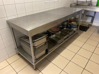 une grande table en inox sur laquelle sont posés tout un tas de plats