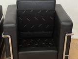 pair of black leather lounge chairs with chrome legs and arms