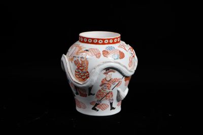 un vase blanc orné d'un motif rouge et orange