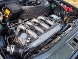 the engine of a car with its hood open and a tire in the trunk