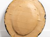 a cardboard plate sitting on the floor next to a white wall