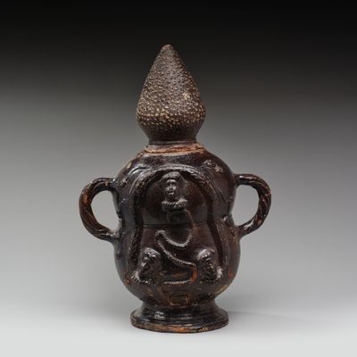 une image représentant un vase marron orné d'un visage