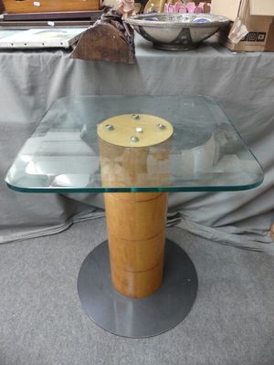une table en verre avec un piètement en bois et un bol posé dessus