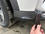 a hand that is holding a measuring tape near a car