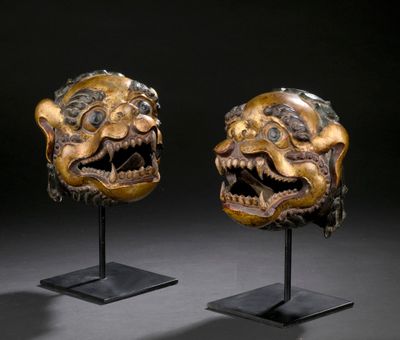 a pair of carved masks on stands with a black background