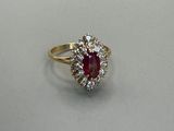 a close up of a ring with a red stone surrounded by white diamonds