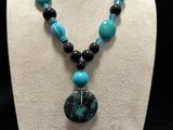 a necklace with a blue and black bead and a black pendant