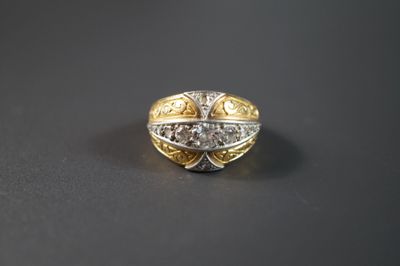 un gros plan d'une bague en or et en argent posée sur une surface noire