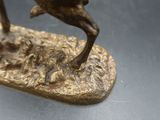 une statue en bronze représentant un homme à cheval sur une planche de surf