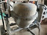 cement mixer sitting in a garage with a wheel on it ' s side