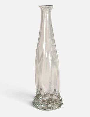 un vase en verre transparent posé sur une surface blanche