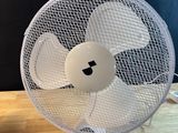 a white fan sitting on top of a wooden table