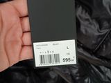 someone is holding a black jacket with a price tag in their hand