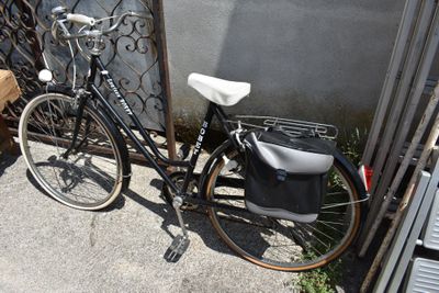 a bicycle parked next to a fence with a bag on it