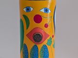 yellow vase with a face painted on the side of it