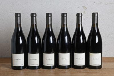 six bouteilles de vin sont alignées sur une table en bois