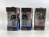 Trois figurines de Star Wars sont posées dans leurs boîtes sur une table