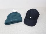 Deux chapeaux sont posés sur un lit, avec une étiquette attachée dessus.