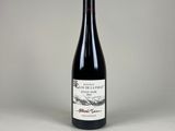 une bouteille de vin rouge posée sur une table blanche