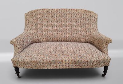 un fauteuil rembourré dont le dossier et les accoudoirs sont recouverts d'un tissu à motifs