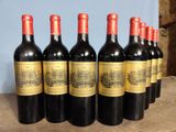 six bottles of red wine are lined up on a wooden table