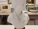 a bust of a woman sitting on a table in front of a painting