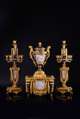 three gold and black vases and a clock on a black surface