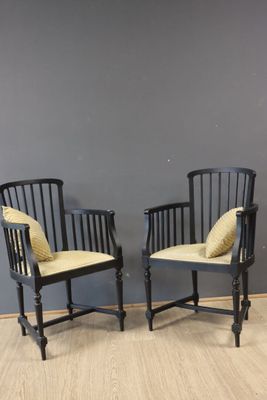 two black chairs with yellow cushions against a gray wall