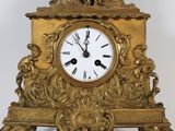 a gold clock with a statue on top of it