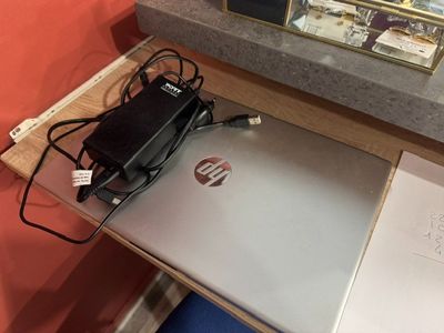 un ordinateur portable posé sur un bureau, avec un chargeur branché dessus