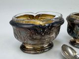 two silver bowls and spoons sitting on a table