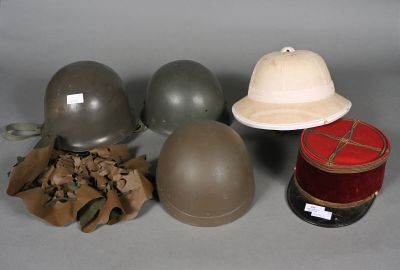 three helmets, a hat, and a spool of thread sit on a table