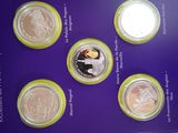 six different coins are in a display case on a purple surface