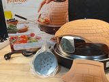 a pizza oven sitting on a table with a cookbook on it