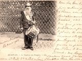 une vieille photo représentant un homme avec un tambour devant une clôture