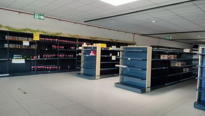 many empty shelves in a store with sodas on them