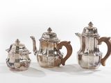 three pieces of silver tea and coffee set on a white surface