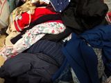 a pile of clothes sitting on a bed next to a pillow