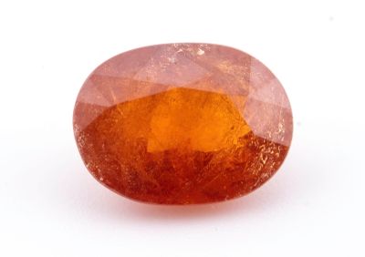 un gros plan d'un saphir orange de forme ovale posé sur une surface blanche